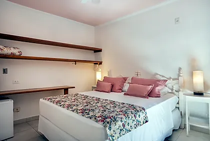 Quarto Clássico da Casa Linda Camburi, com cama de casal e prateleiras de madeira