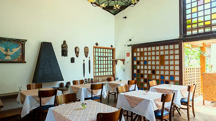 Salão de café da manhã da Casa Linda, com pé-direito alto e vitral colorido
