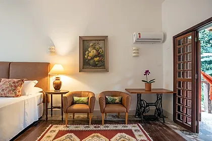Quarto King com Varanda: cama king, poltronas de couro e porta para a varanda